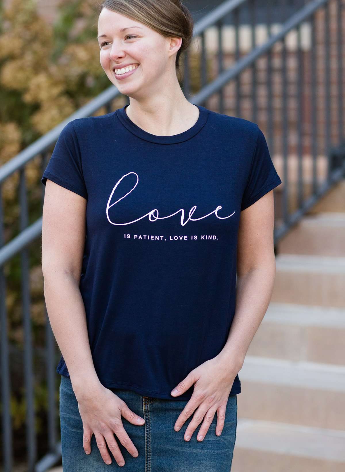 Young woman wearing a love is patient king james version bible verse graphic navy tee