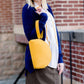 A faux leather crossbody bag. This bag has zippers and pockets along with a detachable strap. This is a mustard color with a slight snake print pattern.