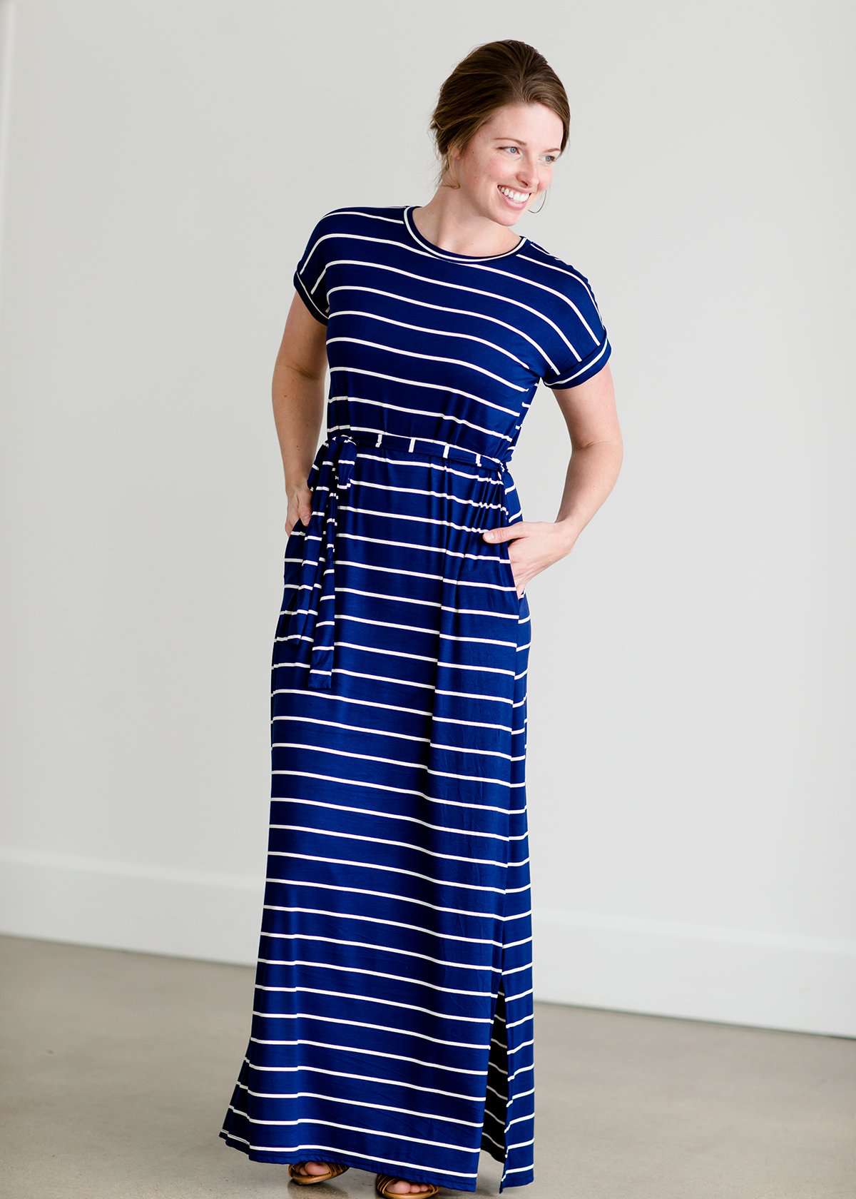 Woman wearing a modest navy and white stripe maxi dress that has cap sleeves and a fabric belt that is detachable!