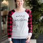 Model woman wearing a grey long sleeve tee with buffalo plaid sleeves and the script font that reads Merry Christmas. 