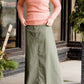Woman wearing an olive, long modest cotton skirt. This skirt has no slit and is paired with a mauve sweater.
