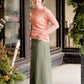 Woman wearing an olive, long modest cotton skirt. This skirt has no slit and is paired with a mauve sweater.