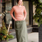 Woman wearing an olive, long modest cotton skirt. This skirt has no slit and is paired with a mauve sweater.