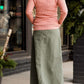 Woman wearing an olive, long modest cotton skirt. This skirt has no slit and is paired with a mauve sweater.