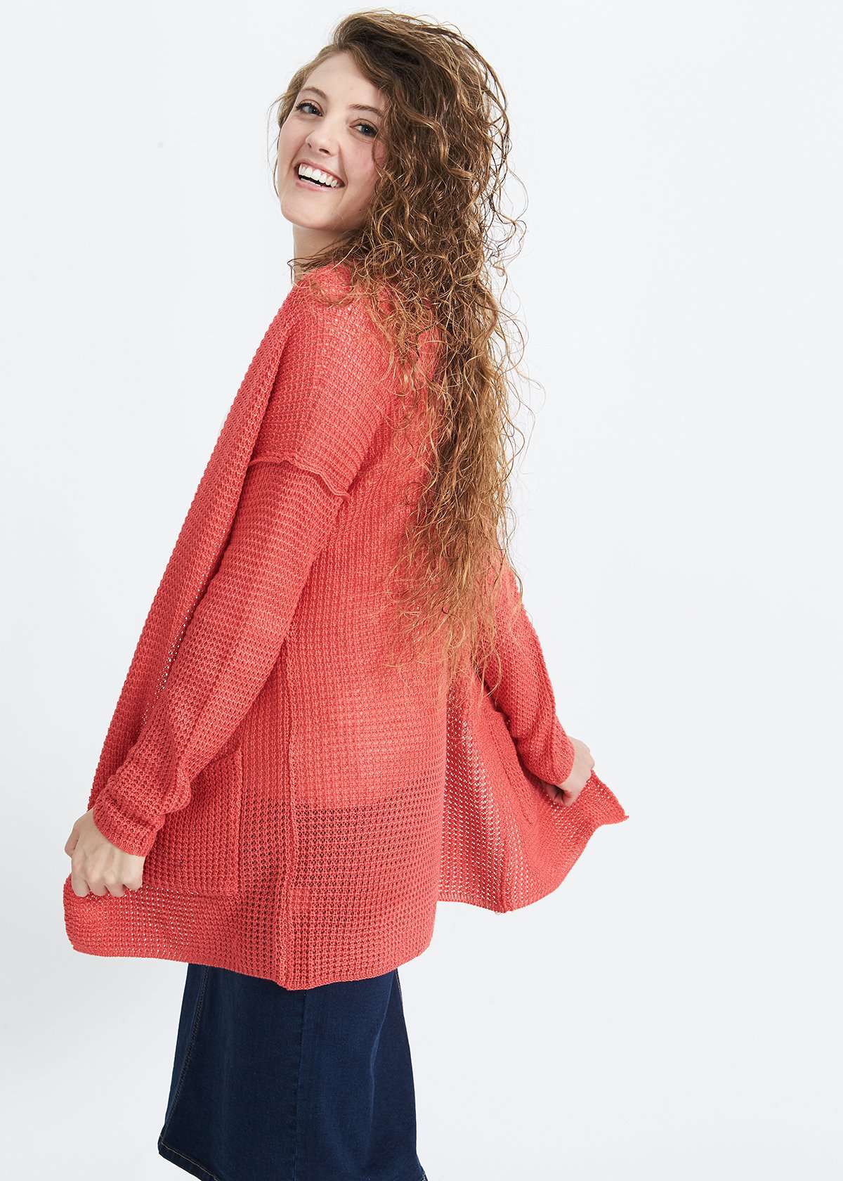 Woman wearing a green or coral waffle knit cardigan