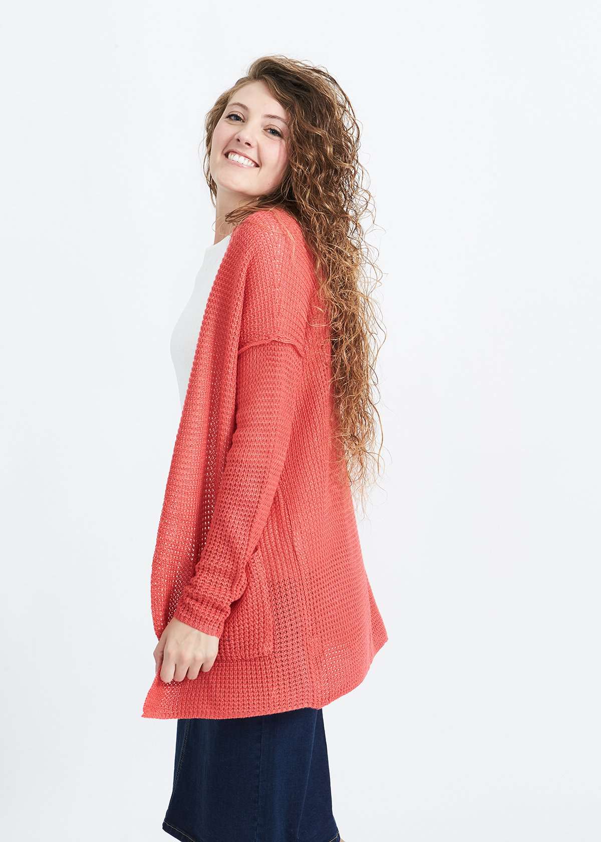 Woman wearing a green or coral waffle knit cardigan