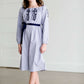Tween wearing a navy boho pin stripe peasant dress with a self tie belt