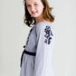 Tween wearing a navy boho pin stripe peasant dress with a self tie belt