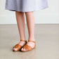 Tween wearing a navy boho pin stripe peasant dress with a self tie belt