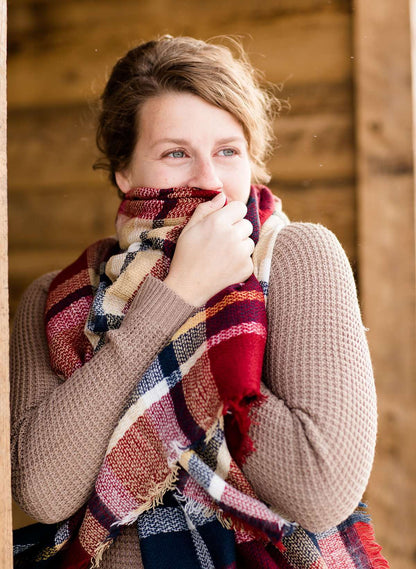 Woman wearing a plaid blanket scarf. Colors range from white, mint, black, yellow, green and blue.