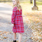 Young girl wearing a modest red plaid midi dress with balloon style sleeves. This dress also features a self tie fabric waist and is lined.
