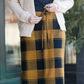 Woman wearing a modest plaid sweater style midi skirt. This skirt has an elastic waist and a tie front. It is paired with tights and short ankle boots.