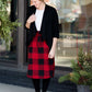 Woman wearing a modest plaid sweater style midi skirt. This skirt has an elastic waist and a tie front. It is paired with tights and short ankle boots.