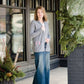 Woman standing in front of Inherit Clothing Company wearing a Minnesota screen printed, gray, open cardigan. The Minnesota screen print is pink.