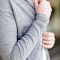 Woman standing in front of Inherit Clothing Company wearing a Minnesota screen printed, gray, open cardigan. The Minnesota screen print is pink.