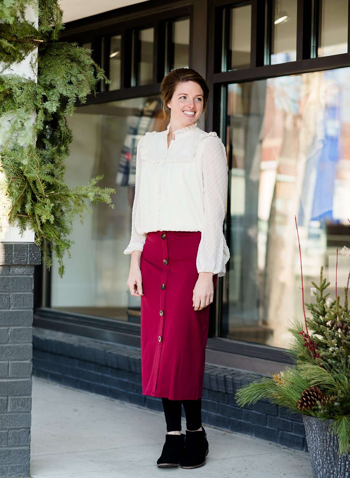 Modest below the knee wine colored skirt. This skirt has faux buttons and is paired with a white blouse and black boots.