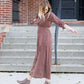 Woman on staircase wearing a rust colored, geometric print, smock maxi dress.