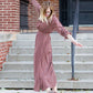 Woman on staircase wearing a rust colored, geometric print, smock maxi dress.