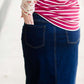 Woman wearing a long denim jean skirt that has a dark wash and a light wash. this is a long modest jean skirt.