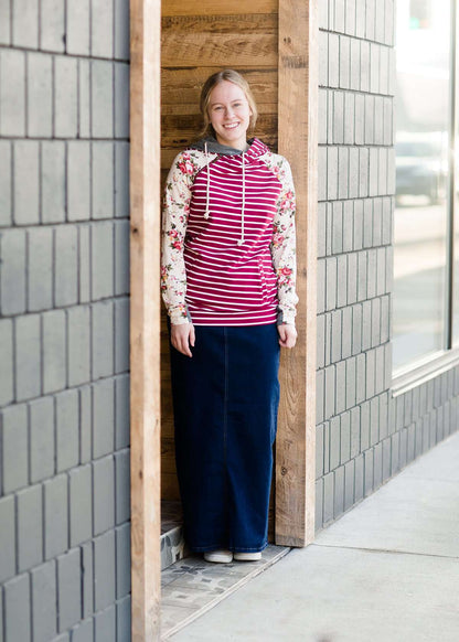 Woman wearing a long denim jean skirt that has a dark wash and a light wash. this is a long modest jean skirt.