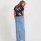 Woman wearing a long denim jean skirt that has a dark wash and a light wash. this is a long modest jean skirt.