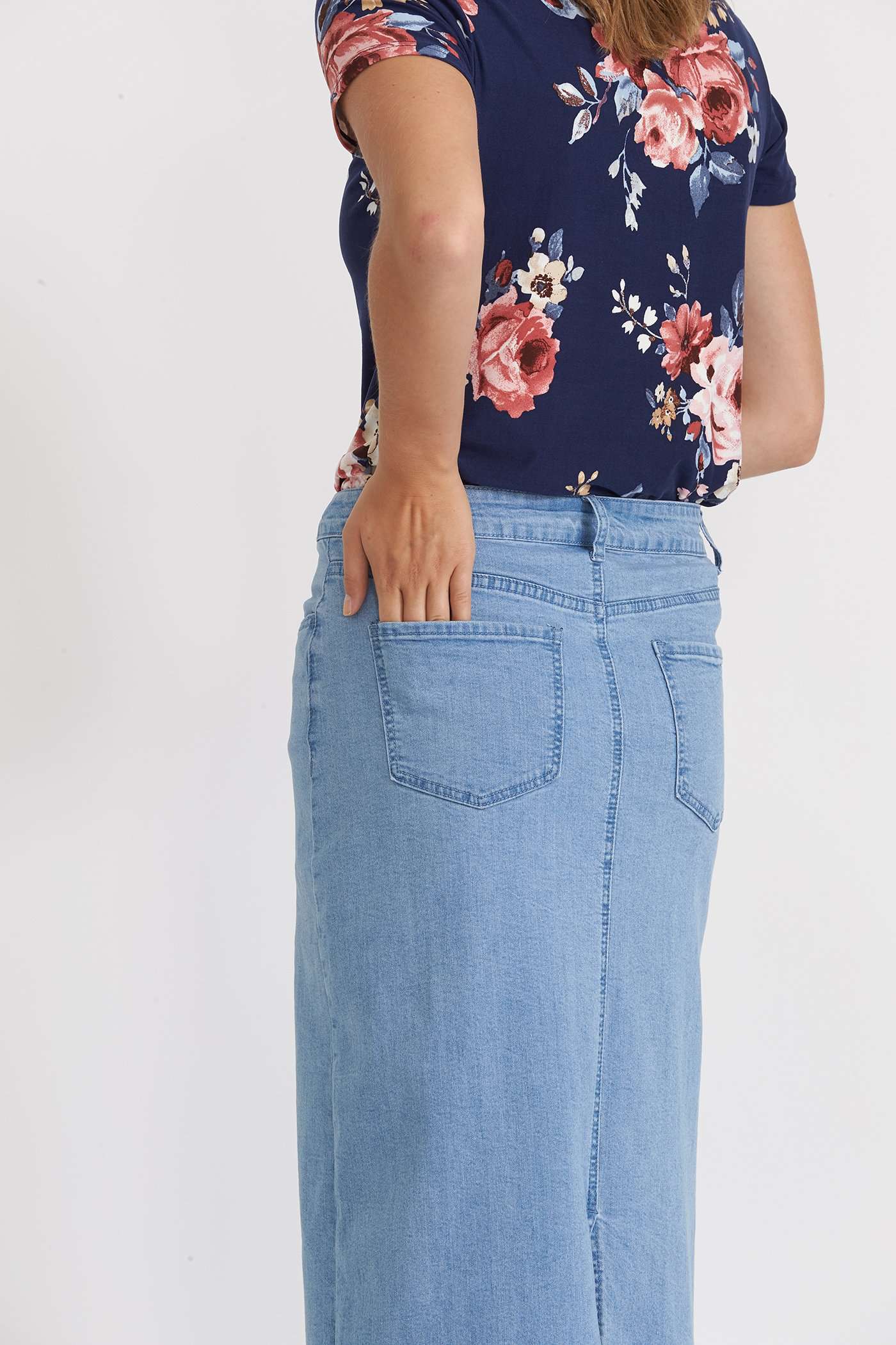 Woman wearing a long denim jean skirt that has a dark wash and a light wash. this is a long modest jean skirt.