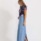 Woman wearing a long denim jean skirt that has a dark wash and a light wash. this is a long modest jean skirt.