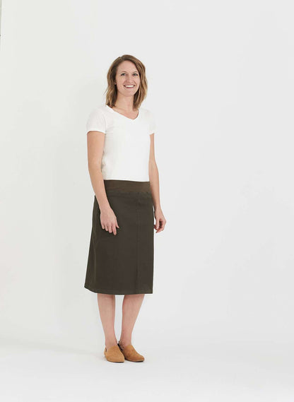Woman wearing a colored, denim-like skirt with a elastic waistband. This is a modest skirt that falls below the knee. It comes in Burgundy, olive, khaki, black and navy. It is also paired with a white v-neck t-shirt.