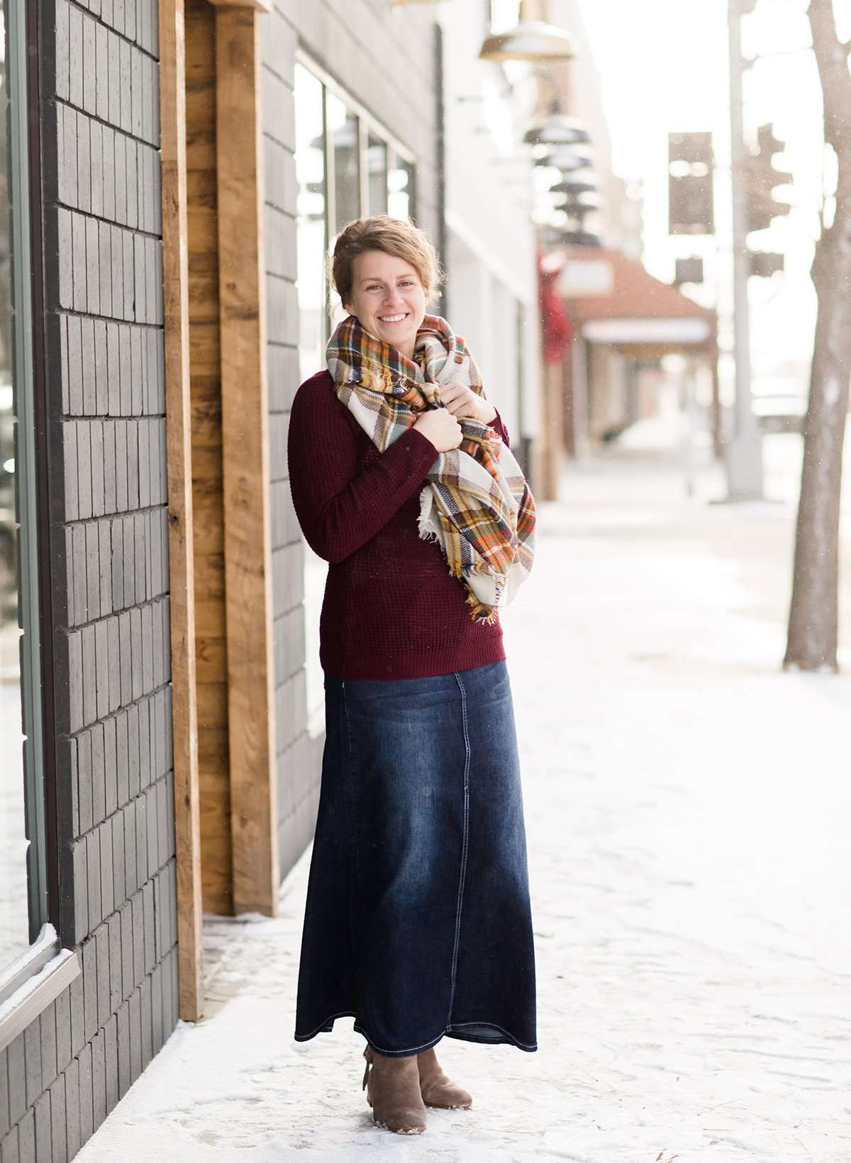Woman wearing a long denim jean skirt with a Burgundy waffle knit sweater in a blanket scarf.