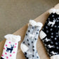 Reindeer Christmas scene slipper socks in gray, cream and black.
