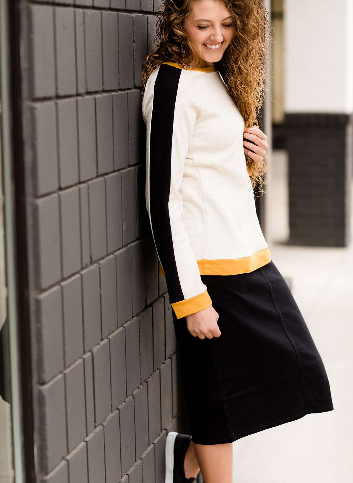 Woman wearing a black below the knee denim midi skirt.