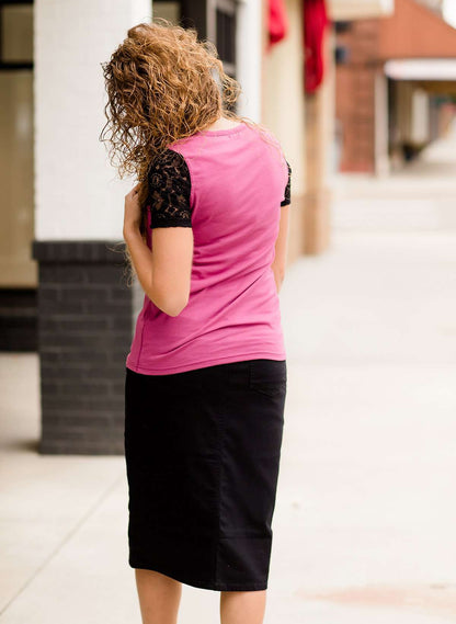 Woman wearing a black below the knee denim midi skirt.