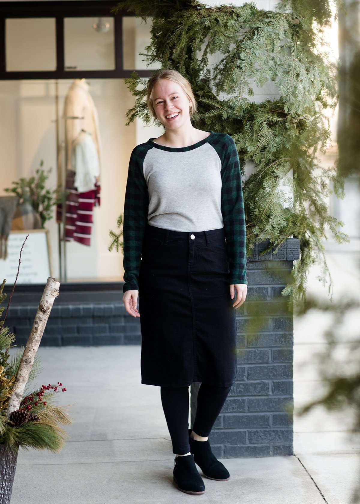 Woman wearing a black below the knee denim midi skirt.