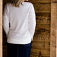woman wearing a reversible knit top in purple and white 