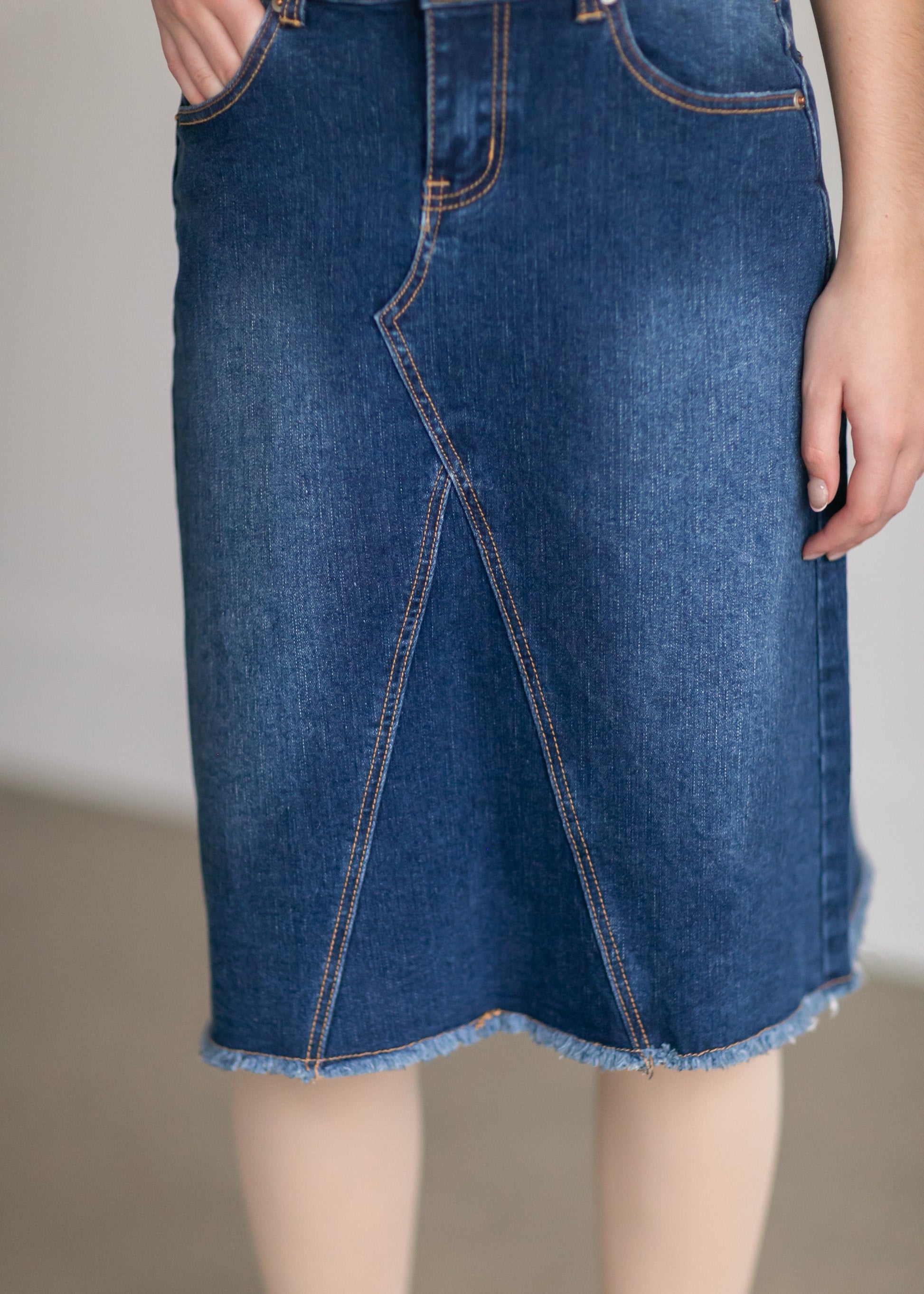 The Riley Frayed Hem Denim Midi Skirt is an Inherit Design that is full of lovely details! It is tailored in a slight a-line fit and super comfortable for anyone wanting that timeless look! This skirt is a darker wash with contrast stitching with a v-stitch in the front and back. You will love the raw bottom hem and the faux leather patch on the back!