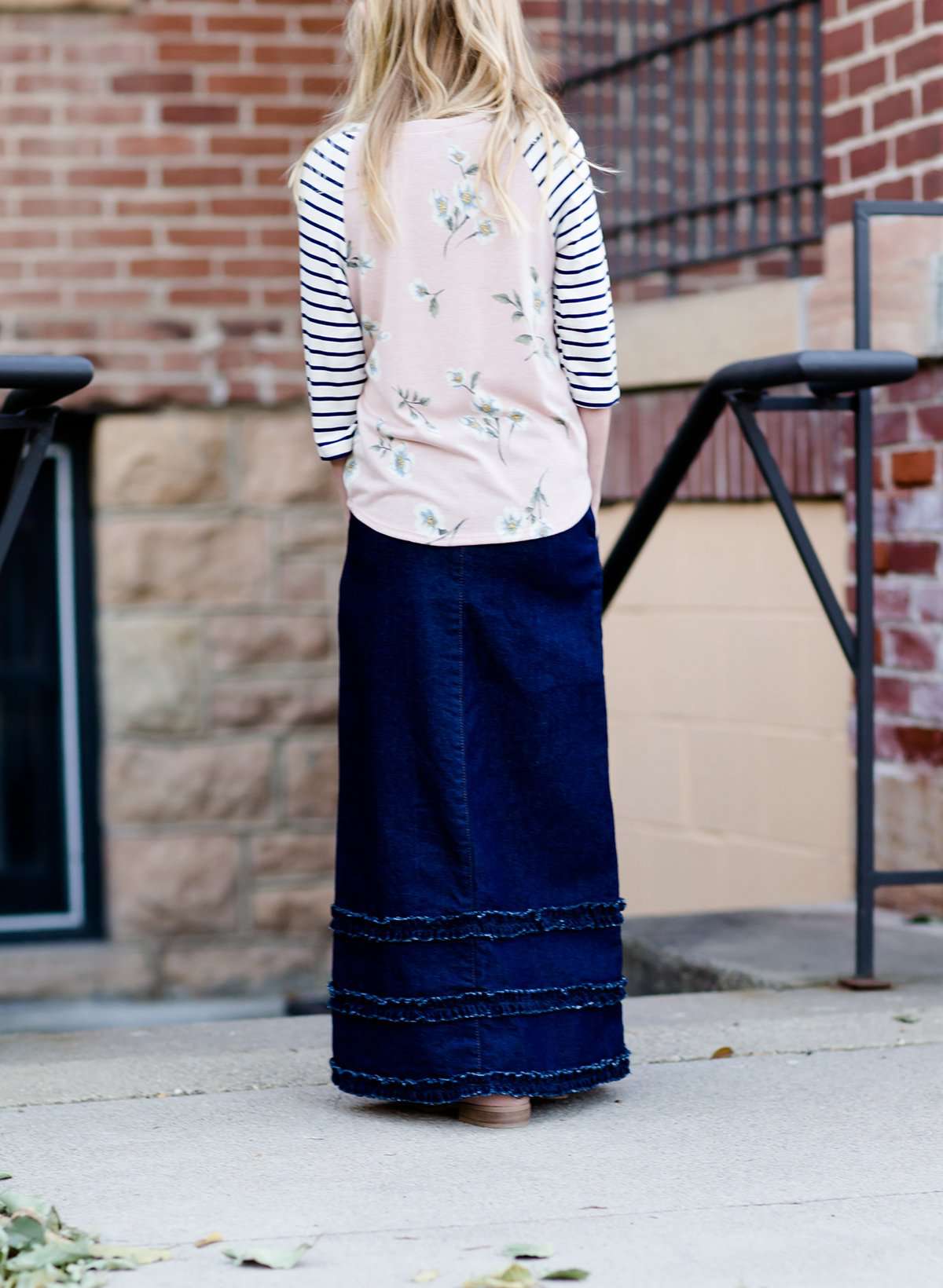 Modest girl wearing a long denim skirt with ruffles on the bottom hem