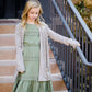 Young girl wearing a sage colored ruffle dress with lace trim on the tiers of the ruffles.