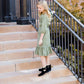 Young girl wearing a sage colored ruffle dress with lace trim on the tiers of the ruffles.
