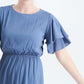 woman wearing a dusty blue empire waist dress with double ruffle sleeves that is lined and falls below the knee