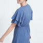 woman wearing a dusty blue empire waist dress with double ruffle sleeves that is lined and falls below the knee
