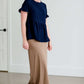 Woman wearing a navy peplum baby doll top that has ruffle details on the sleeves.