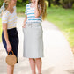 Woman wearing a below the knee sweatshirt material skirt that has pockets and drawstrings. This skirt is black, navy and gray.
